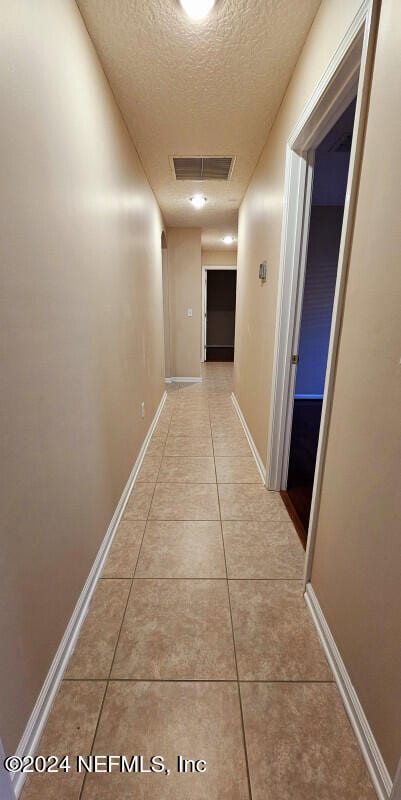 corridor with light tile patterned floors and a textured ceiling