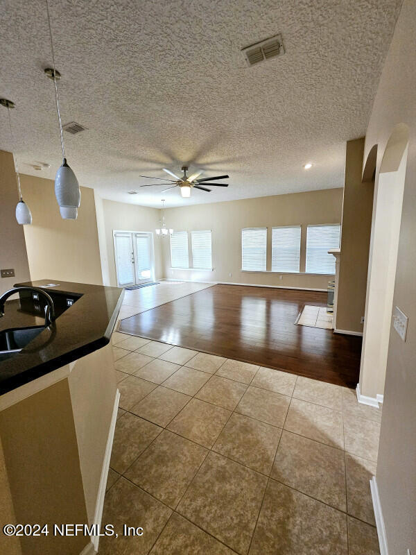 interior space with ceiling fan, sink, hanging light fixtures, light hardwood / wood-style floors, and a textured ceiling