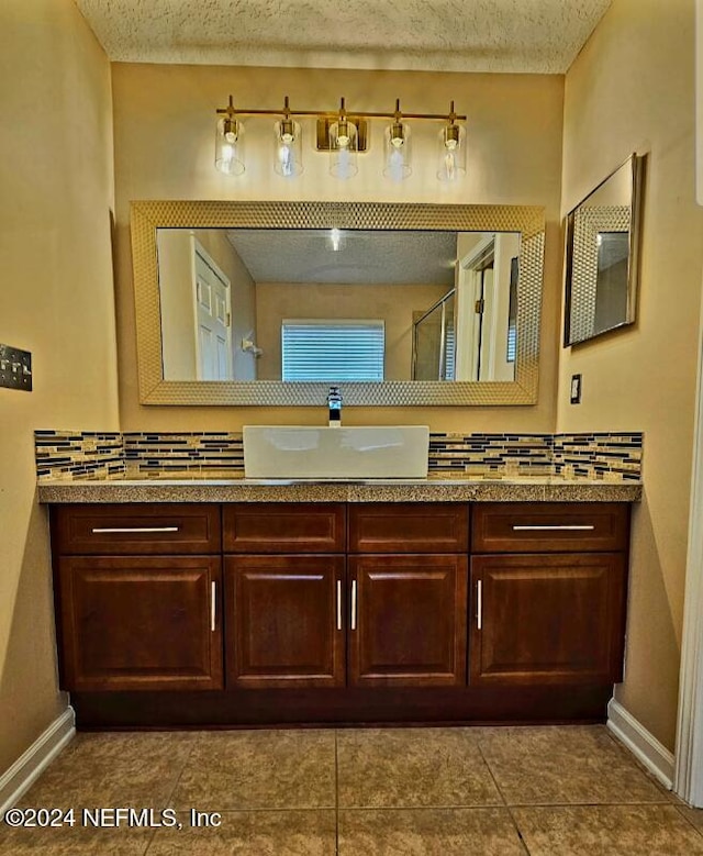 bathroom featuring tile patterned flooring, a textured ceiling, vanity, and tasteful backsplash