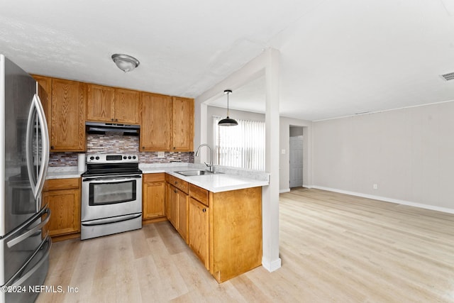 kitchen featuring sink, tasteful backsplash, light hardwood / wood-style floors, decorative light fixtures, and appliances with stainless steel finishes