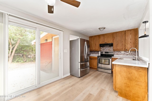 kitchen featuring pendant lighting, sink, light hardwood / wood-style flooring, decorative backsplash, and stainless steel appliances