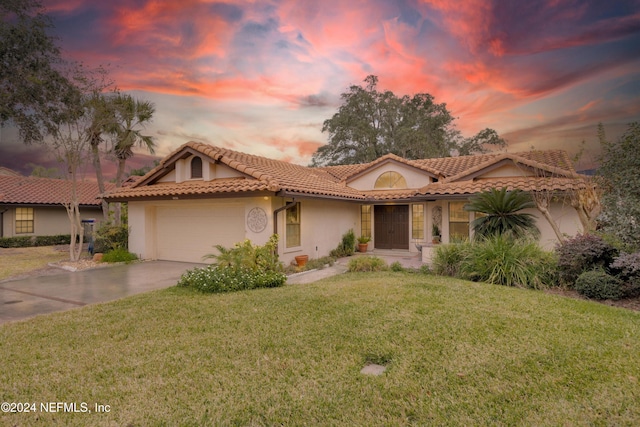 mediterranean / spanish house with a lawn and a garage