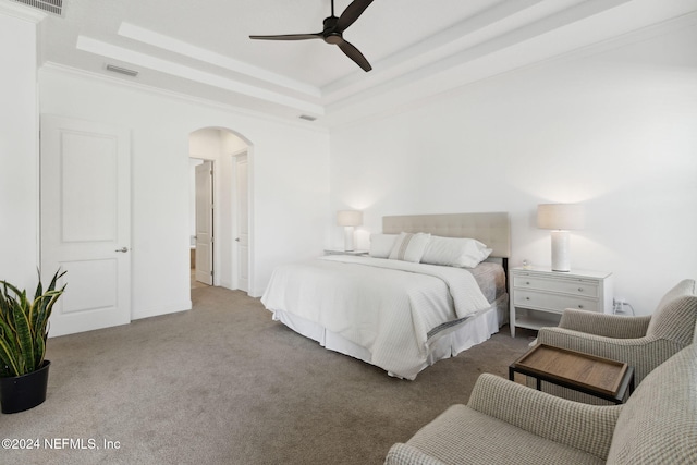 bedroom featuring ceiling fan, a raised ceiling, carpet floors, and ornamental molding