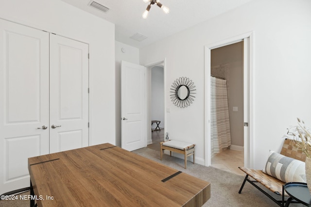 carpeted home office featuring a chandelier