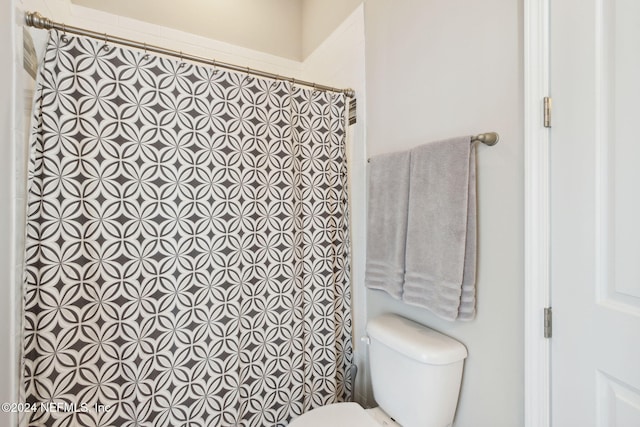 bathroom featuring toilet and curtained shower