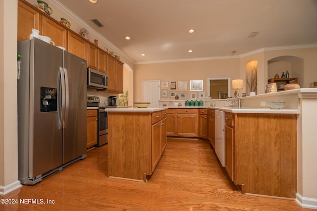 kitchen featuring stainless steel appliances, kitchen peninsula, light wood-type flooring, a kitchen island, and ornamental molding