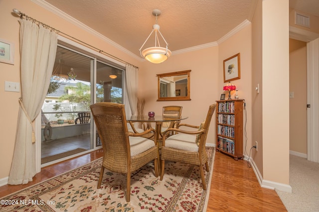 dining room featuring a textured ceiling, light wood-type flooring, and ornamental molding