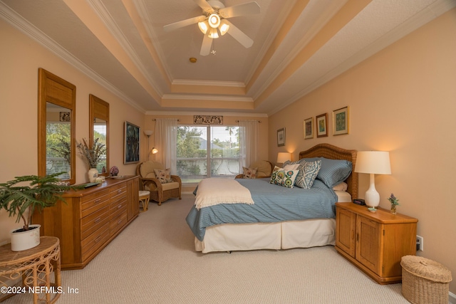 bedroom featuring ceiling fan, light colored carpet, ornamental molding, and a tray ceiling