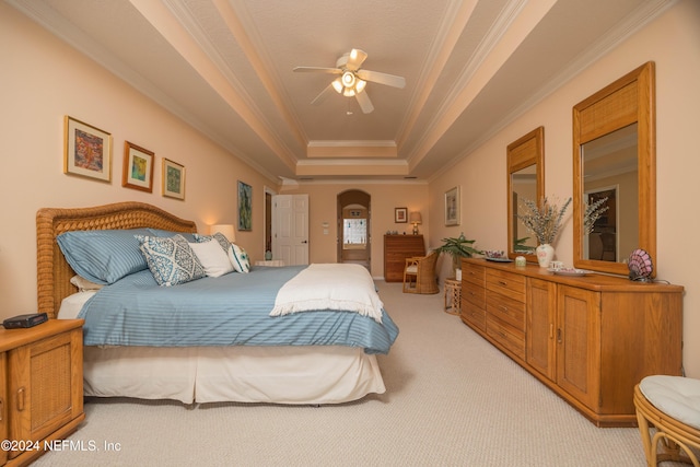 bedroom featuring ceiling fan, a raised ceiling, light colored carpet, and crown molding