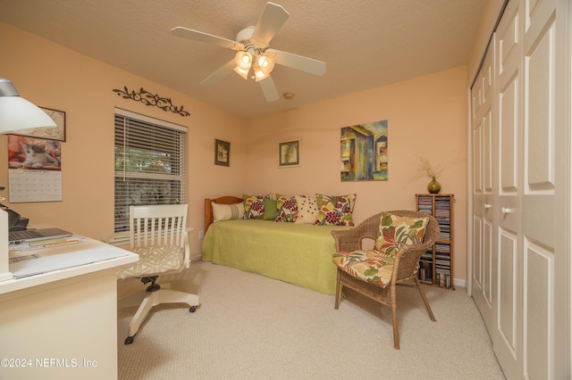 bedroom with ceiling fan, a closet, light colored carpet, and a textured ceiling