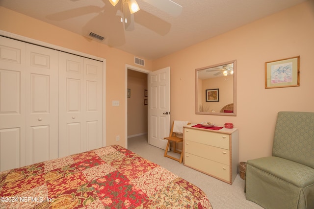 bedroom featuring a textured ceiling, a closet, light colored carpet, and ceiling fan