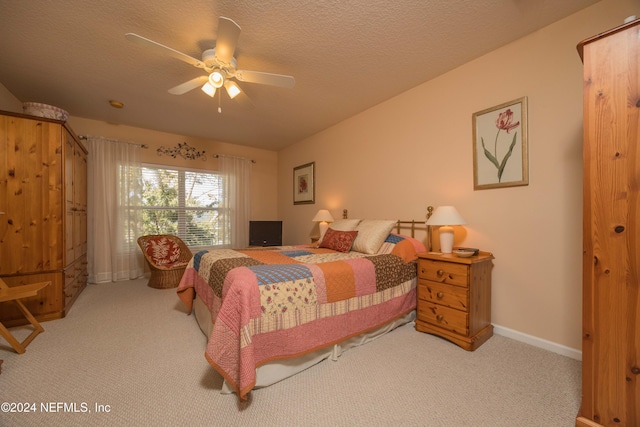 bedroom with ceiling fan, light carpet, and a textured ceiling