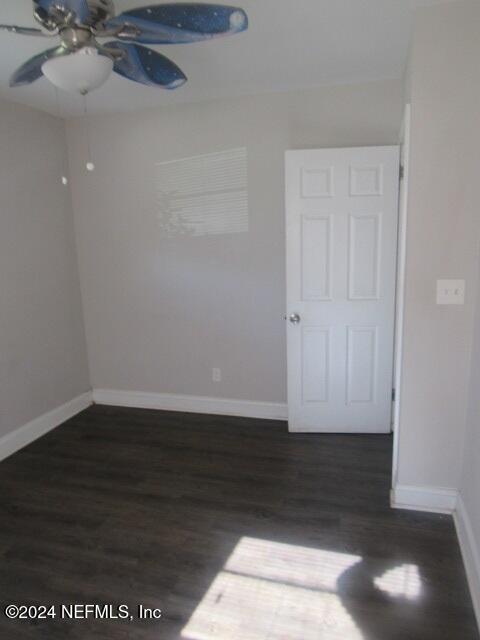 unfurnished room featuring ceiling fan and dark wood-type flooring