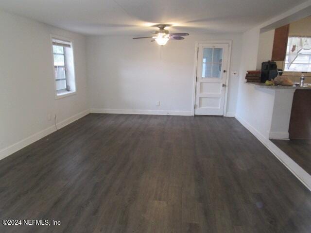 unfurnished living room featuring plenty of natural light, dark hardwood / wood-style floors, and ceiling fan