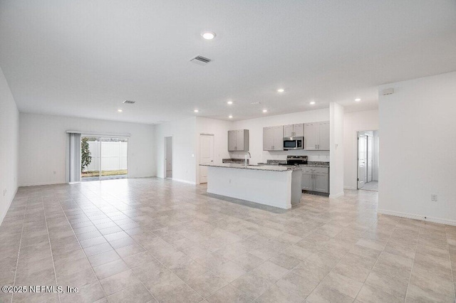 kitchen with gray cabinets, appliances with stainless steel finishes, sink, a kitchen island with sink, and light tile patterned floors