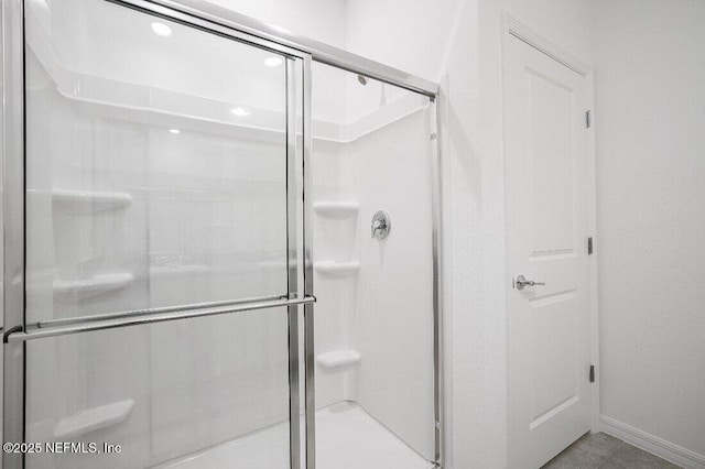 bathroom with an enclosed shower and tile patterned floors