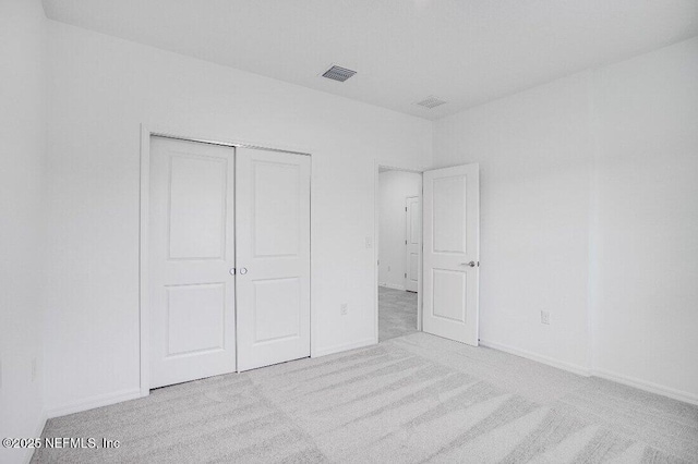 unfurnished bedroom with light colored carpet and a closet