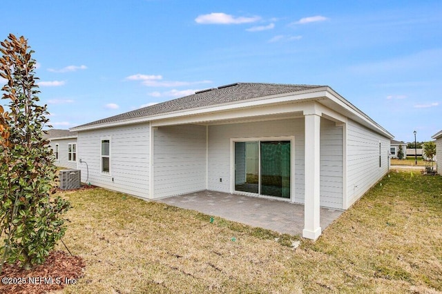 rear view of house with central air condition unit, a patio, and a lawn