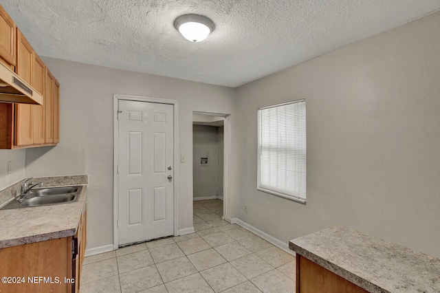 kitchen featuring a textured ceiling, light tile patterned flooring, and sink