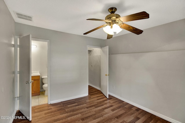 unfurnished bedroom with dark hardwood / wood-style flooring, ensuite bath, and ceiling fan