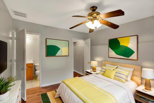 bedroom featuring connected bathroom, light hardwood / wood-style flooring, and ceiling fan