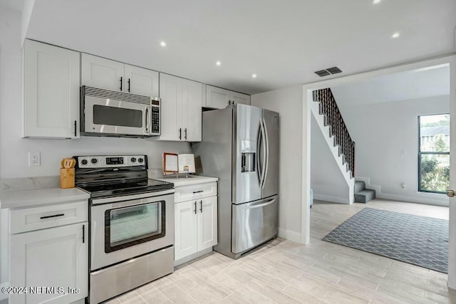 kitchen featuring white cabinets, light wood-type flooring, and stainless steel appliances