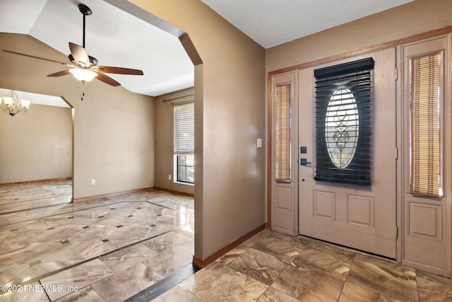 entrance foyer featuring a textured ceiling, ceiling fan with notable chandelier, and lofted ceiling