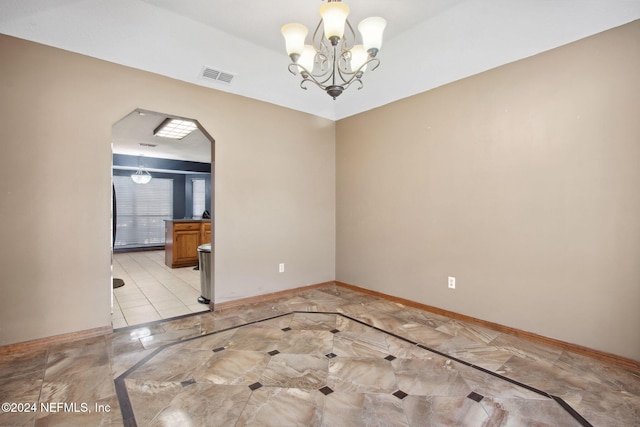 unfurnished room featuring a notable chandelier