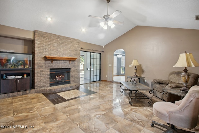 living room featuring ceiling fan, vaulted ceiling, and a brick fireplace