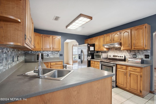 kitchen featuring decorative backsplash, kitchen peninsula, stainless steel appliances, sink, and light tile patterned floors