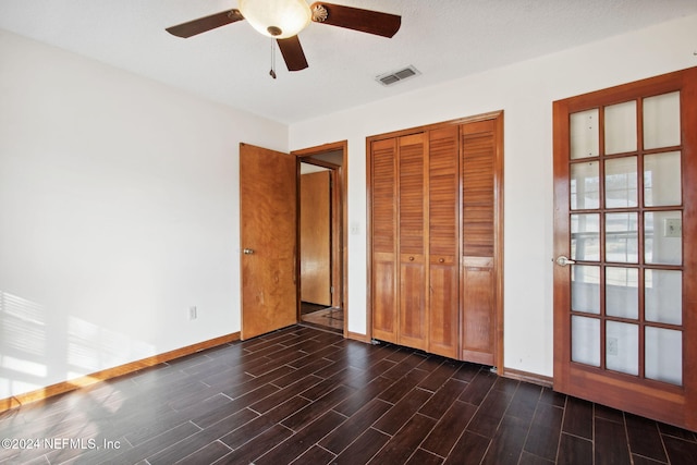 unfurnished bedroom featuring ceiling fan, a closet, dark wood-type flooring, and a textured ceiling