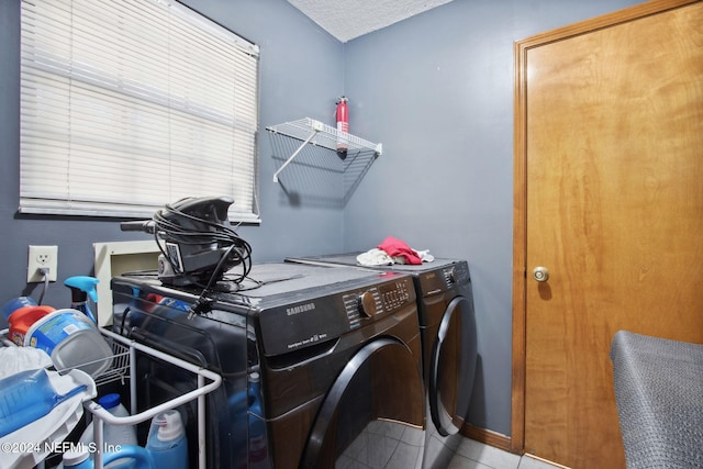 laundry room with a textured ceiling, washer and clothes dryer, and light tile patterned flooring