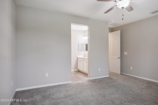 unfurnished bedroom with ceiling fan, light colored carpet, and ensuite bath