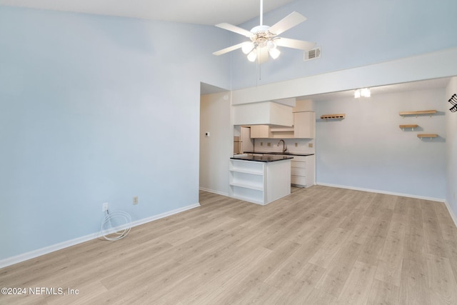 unfurnished living room featuring ceiling fan, light hardwood / wood-style floors, sink, and high vaulted ceiling