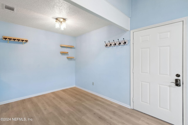 unfurnished room featuring a textured ceiling and light hardwood / wood-style flooring