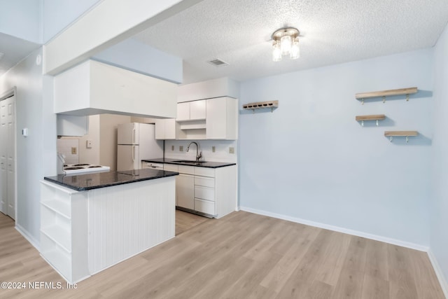 kitchen featuring kitchen peninsula, sink, white refrigerator, light hardwood / wood-style flooring, and white cabinets