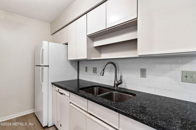 kitchen with white dishwasher, sink, hardwood / wood-style flooring, dark stone countertops, and white cabinets