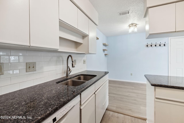 kitchen with dark stone counters, sink, white cabinets, and light hardwood / wood-style floors