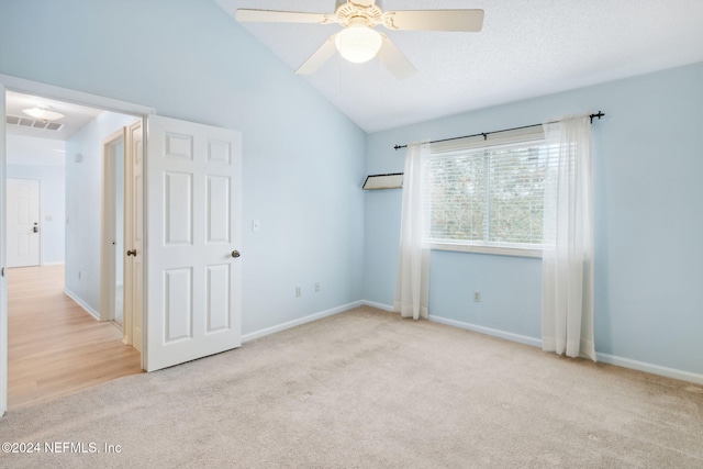 carpeted empty room featuring vaulted ceiling and ceiling fan