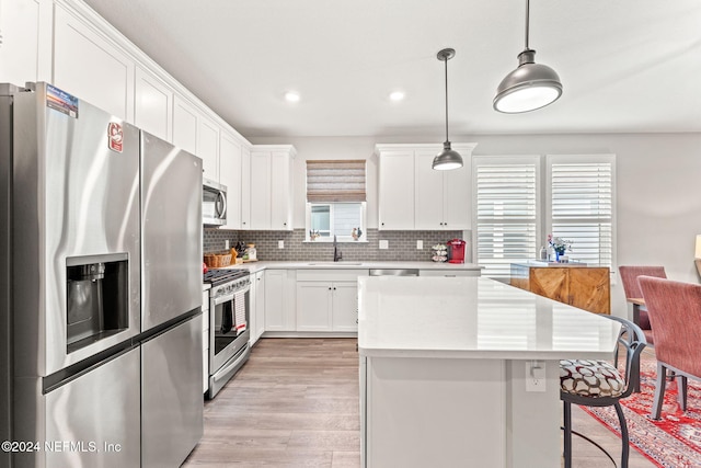 kitchen featuring appliances with stainless steel finishes, light hardwood / wood-style flooring, plenty of natural light, and pendant lighting