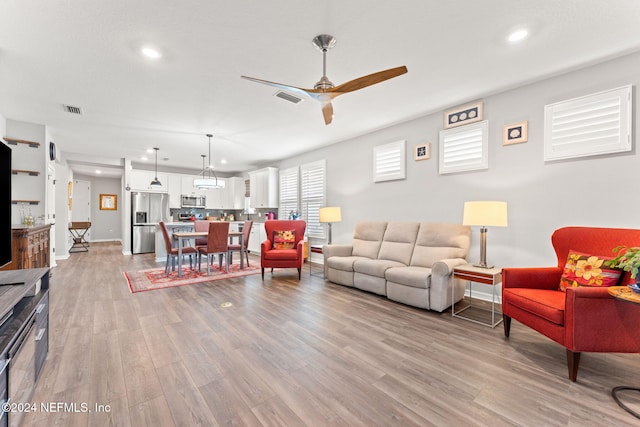 living room featuring light wood-type flooring and ceiling fan