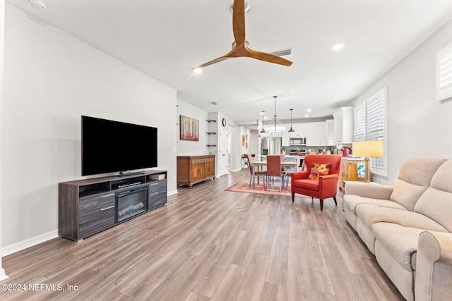 living room with ceiling fan and light hardwood / wood-style flooring