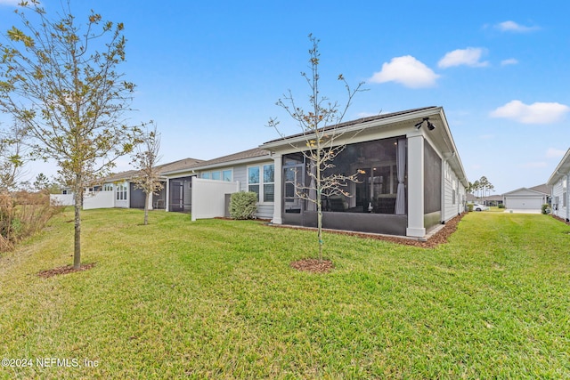 back of property featuring a sunroom and a lawn