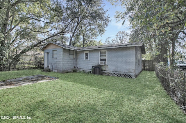 rear view of property with a lawn and cooling unit