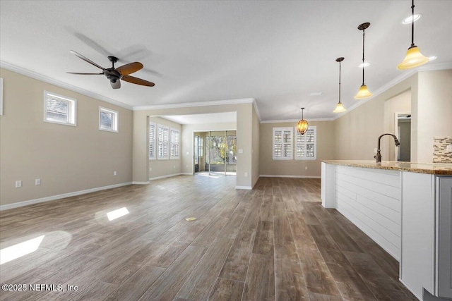 unfurnished living room with ceiling fan, ornamental molding, dark hardwood / wood-style flooring, and sink