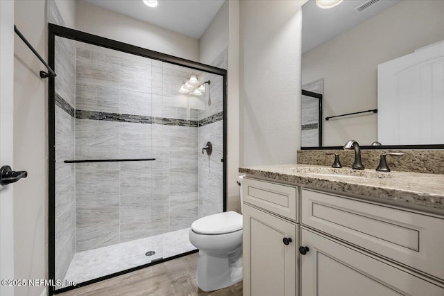 bathroom with vanity, toilet, and a shower with door