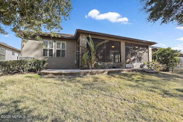 rear view of property featuring a yard and a sunroom