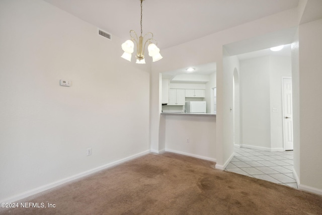 carpeted spare room featuring a chandelier