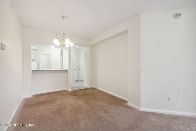 carpeted spare room with a notable chandelier