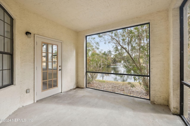 unfurnished sunroom featuring a water view